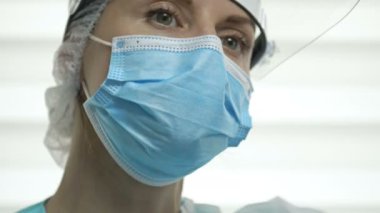 Yorgun bir kadın doktor ya da hemşire portresi. Kadın gözlüğünü çıkarıp maskesini takıyor ve zevkle kahve içiyor. Covid-19 salgını sırasında sağlık çalışanlarının günlük yaşamları acımasızdı..