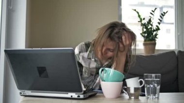 Evde dizüstü bilgisayarla çalışan çok yorgun bir iş kadını. Masada birkaç boş çay ve kahve var. Kadın yorgunluktan uyuyakalıyor. Fazla çalışma kavramı.