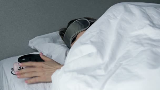 Женщина ненавидит рано вставать по утрам. Сонная женщина смотрит на будильник и пытается спрятаться под подушкой. Раннее пробуждение, недосыпание. — стоковое видео
