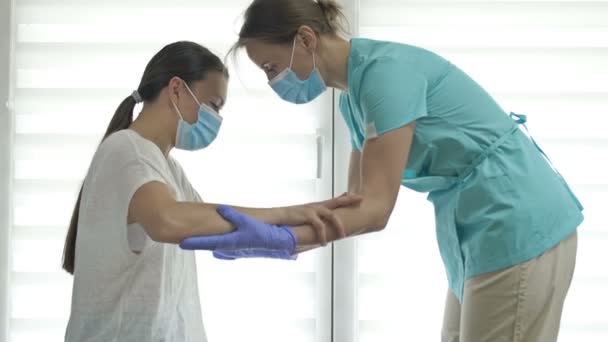 Dokter atau perawat membantu pasien wanita untuk mendapatkan kakinya. Pulih dari cedera, operasi, atau stroke. Perisai wajah. Perawatan selama pandemi Covid-19. — Stok Video