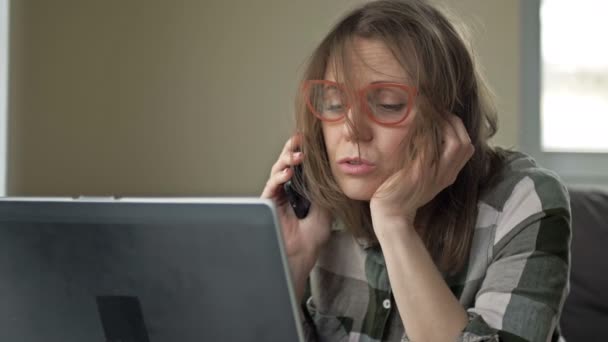 Portrait of a very tired woman. She works at the computer and speaks on the phone. Workaholism. Overtime work. — Stock Video