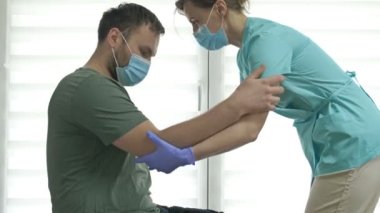 Doktor ya da hemşire bir hastanın ayağa kalkmasına yardım ediyor. Yaralanma, ameliyat ya da felç sonrası iyileşme. Covid-19 salgını sırasında tedavi.