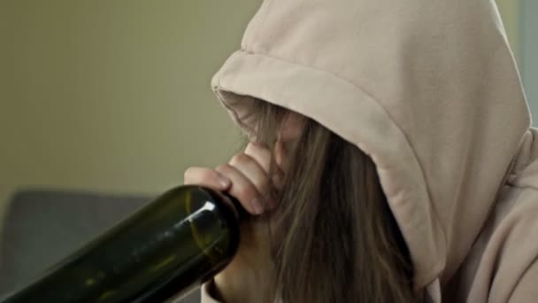 An unkempt woman is drinking wine from a bottle alone. The social problem of female alcoholism. — Stock Video