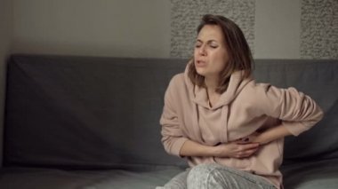Kanepede oturan kadın karnının sol tarafında keskin, ani bir ağrı ile delinmiş..