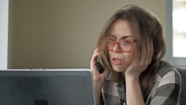 一个非常疲倦的女人的画像。她在电脑上工作，在电话上说话。工作狂主义。加班工作. — 图库视频影像
