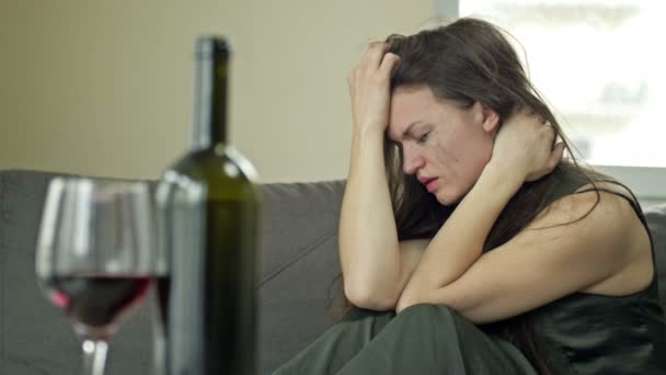 Płacząca młoda, przygnębiona kobieta - ofiara przemocy domowej lub znęcania się próbuje złagodzić cierpienie alkoholem. Przemoc domowa. — Wideo stockowe