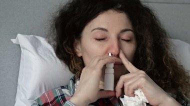 Grip, soğuk algınlığı ya da koronavirüs belirtileri gösteren orta yaşlı bir kadının portresi. Bir kadın burnuna ilaç sıkar..