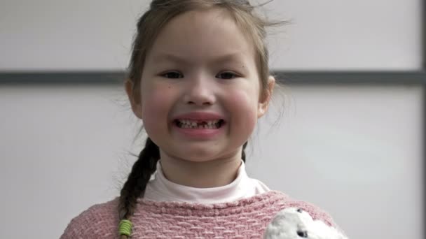 Retrato de uma menina de 6-7 anos regozijando-se com um dente perdido. O conceito de mudança de dentes. — Vídeo de Stock