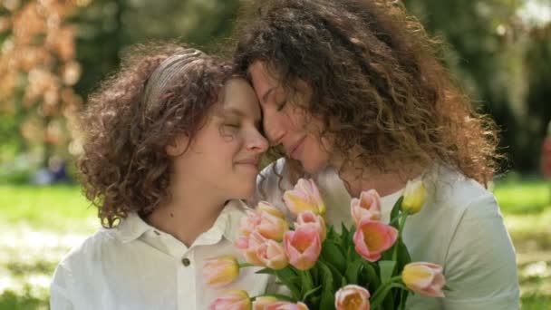Portrét ženy s kyticí tulipánů objímající svou dospívající dceru. Den matek. — Stock video