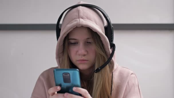 Tenåringsjente som holder telefonen besatt av smarttelefon sosiale medier apper som sitter alene hjemme. Teknologi som er avhengig av tenåringer som spiller mobilspill, sender meldinger, ser på videoer på moderne dingsteknikk. – stockvideo