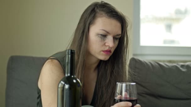 Płacząca młoda, przygnębiona kobieta - ofiara przemocy domowej lub znęcania się próbuje złagodzić cierpienie alkoholem. Przemoc domowa. — Wideo stockowe