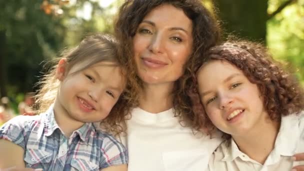 快乐的女人拥抱着两个不同年龄的女儿。每个人都很快乐在一个温泉公园的背景下母亲节. — 图库视频影像