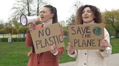 İki kadın ellerinde posterlerle durup gezegeni kurtarıyorlar ve plastikleri yok. Bir tanesi, çevrenin korunması için megafon kullanıyor. Küresel mücadeleye makul bir katkı