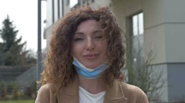 Maske modunun iptali. Orta yaşlı bir kadın sokakta koruyucu maskesini çıkarmaktan mutluluk duyar. Covid-19 salgını azalıyor..