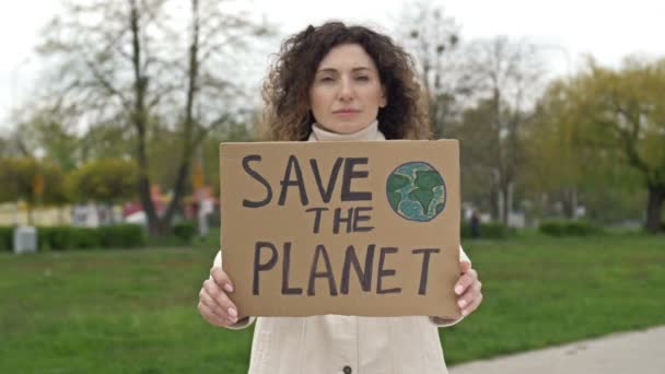 Mujer con un cartel SALVA EL PLANETA. Contribución factible a la lucha contra la contaminación mundial de la naturaleza. Piquete único. — Vídeo de stock