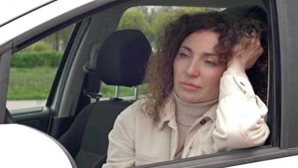 Traurige Frau mittleren Alters sitzt in Gedanken am Steuer ihres Autos. — Stockvideo
