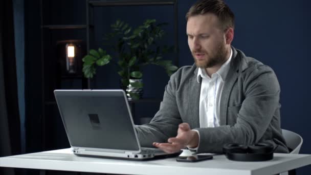 Retrato de un hombre de negocios de mediana edad sentado tarde en la noche frente a una computadora portátil. El hombre está insatisfecho con algo. Fatiga, exceso de trabajo. — Vídeo de stock