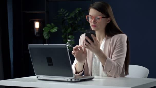 成功的女企业家使用笔记本电脑，在工作中打电话，微笑着与客户取得联系，或通过坐在办公室桌上的手机咨询客户. — 图库视频影像