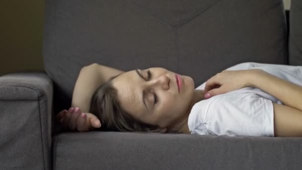 Trøtt kvinne, utslitt, faller på sofaen og kan endelig slappe av og slappe av.. – stockvideo