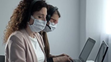 Tıbbi maskeli çağrı merkezi operatörleri. Coronavirüs salgını sırasında ofis işi..