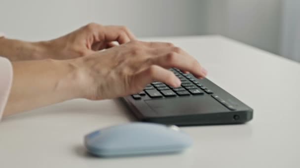 Manos femeninas escribiendo en el teclado y sosteniendo el ratón de la computadora sobre fondo claro — Vídeos de Stock