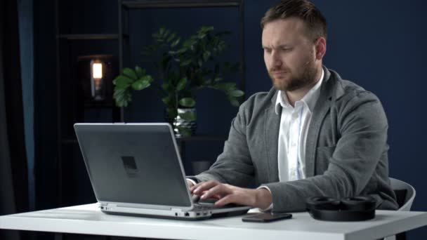 Porträt eines Mannes mittleren Alters, der an einem Laptop arbeitet. Der Mensch ist fokussiert und nachdenklich. Distanzierte Arbeit. — Stockvideo