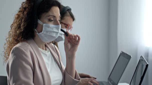 Operadores de centros de llamadas con máscaras médicas. Trabajo de oficina durante la epidemia de coronavirus. — Vídeos de Stock
