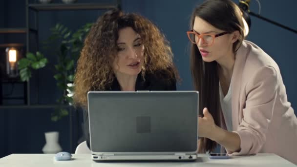 Konzentrierte Kolleginnen sitzen am Schreibtisch im Büro und diskutieren über Geschäftsidee und Laptop. Kooperationskonzept. — Stockvideo