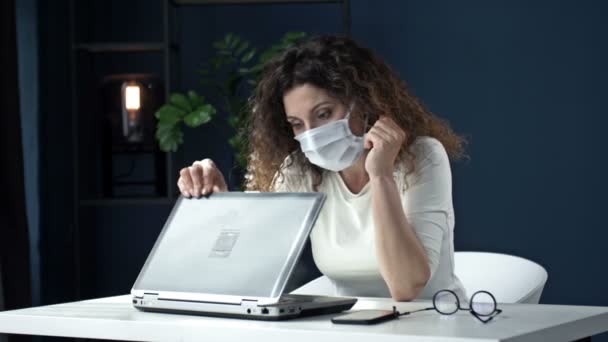 Travailler pendant l'épidémie de coronavirus. Femme d'affaires fatiguée d'âge moyen enlève son casque, ferme son ordinateur portable, et est soulagée de jeter son masque médical ennuyeux à la fin du travail — Video