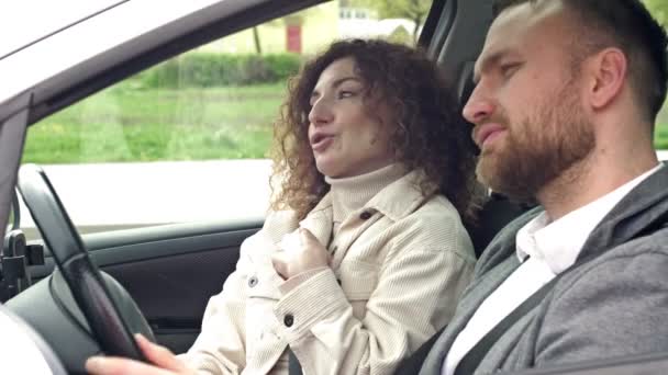 Мужчина и женщина сидят в машине и ссорятся. Женщина что-то доказывает, мужчина отрицательно качает головой.. — стоковое видео
