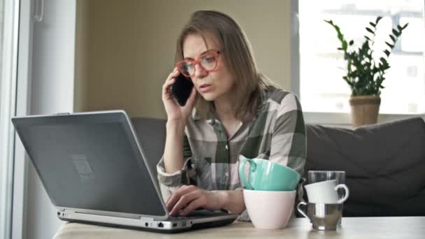 La mujer de negocios que trabaja a distancia está muy cansada al final de la jornada laboral. Hay varias tazas vacías de té y café en la mesa. Concepto de trabajo excesivo. — Vídeo de stock