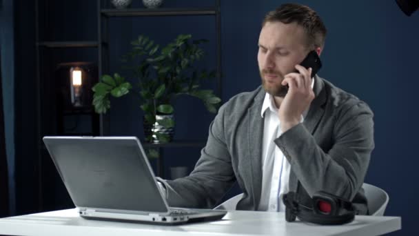 Soustředěný podnikatel. Mladý profesionál používající počítač, který sedí u kancelářského stolu. Pracovník na volné noze pracující na notebooku zařízení a mluví s partnerem. — Stock video