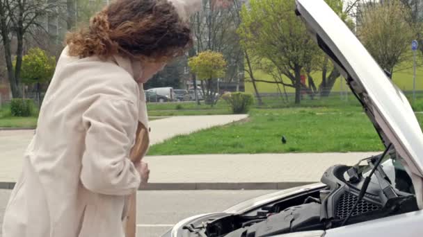 Mujer hablando por teléfono, mirando el motor del coche roto, llamadas al servicio de evacuación, campana abierta, llamada para ayudar, servicio de remolque. — Vídeo de stock