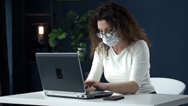 Travailler pendant l'épidémie de coronavirus. Femme d'affaires fatiguée d'âge moyen enlève ses lunettes, un masque médical et ferme son ordinateur portable en soulagement à la fin de la journée de travail. — Video