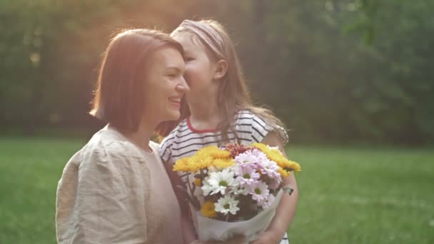 A kislány virágot ad az anyjának. Kedves család együtt. Nyári nap. Családi portré. Boldog anyaságot! Élvezd a természetet. Anyák napja. — Stock videók