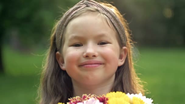 Καλοκαιρινό πορτραίτο ενός χαρούμενου κοριτσιού χωρίς δόντια 6-7 ετών με μπουκέτο λουλούδια. Κοντινό πλάνο. — Αρχείο Βίντεο