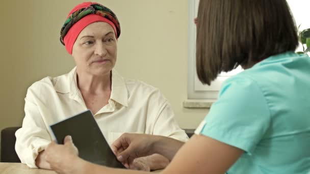 Mujer madura con cáncer que visita al médico en el hospital escuchando sobre la recuperación. Vista posterior del oncólogo contando buenas noticias al paciente después de la quimioterapia. — Vídeos de Stock