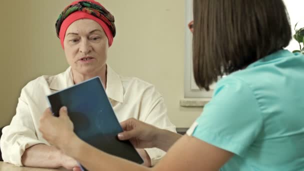 El médico muestra una radiografía a un paciente de cáncer durante una consulta en un centro médico. Paciente femenina está satisfecha con las buenas noticias. — Vídeos de Stock