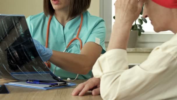 Le médecin montre une radiographie à un patient cancéreux lors d'une consultation dans un centre médical. La patiente est satisfaite des bonnes nouvelles. — Video