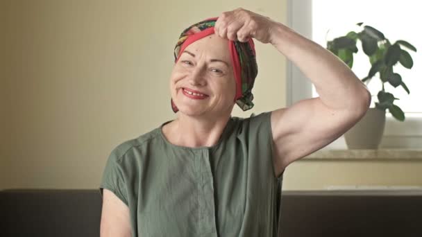 Portret van een vrouw met kanker. Ze haalt de sjaal van haar kale hoofd. Alopecia als gevolg van chemotherapie. Er zijn tranen in haar ogen van pijn, angst en wanhoop.. — Stockvideo