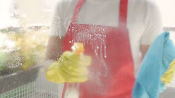 노란색 장갑을 끼고 실내복을 세탁하는 여성 손에 헝겊 과 스프레이 세제를 사용 한다. 물보라로 창문을 닦는 일. — 비디오