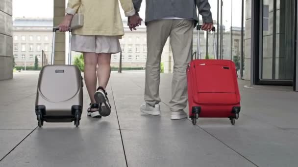 Paar mit Koffern auf dem Weg durch den Flughafen oder Bahnhof. Rückseite. — Stockvideo