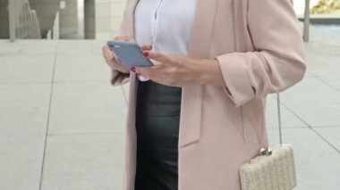 İnterneti kullanarak cep telefonuna mesaj yazan zarif bir iş kadını..