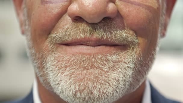 Een close-up. Een deel van het gezicht van een glimlachende volwassen man met een grijze baard. — Stockvideo