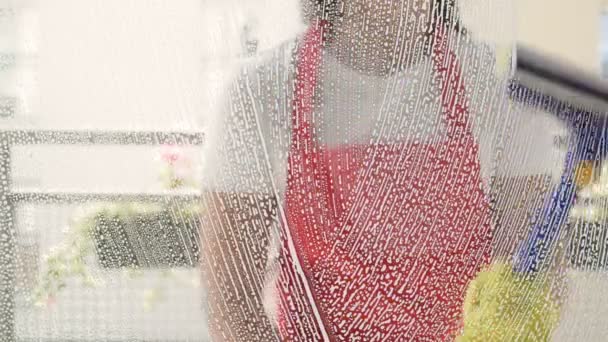Petugas kebersihan atau ibu rumah tangga mencuci jendela dengan menggunakan deterjen dan pembersih jendela. — Stok Video