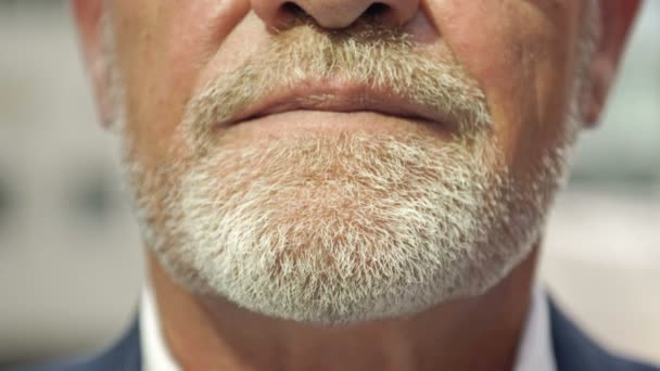 Close-up. Parte do rosto de um homem maduro sorridente com uma barba cinza. — Vídeo de Stock