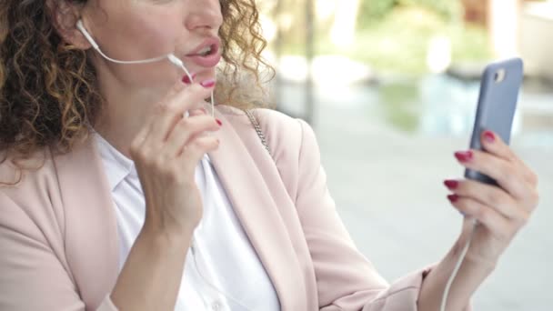 Portrait d'une femme d'affaires capable de travailler dans une rue de la ville avec un téléphone et un casque. Marchez dehors et travaillez dehors. Nouveau mode de vie normal. — Video