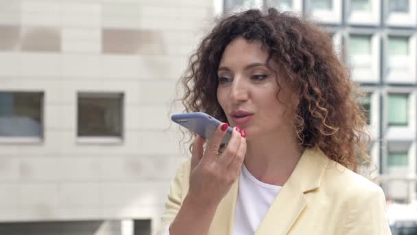 Portret van een mooie volwassen vrouw aan de telefoon op de binnenplaats van een kantoorcentrum. — Stockvideo