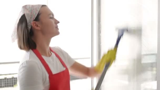 Vacker ung hemmafru tvättar fönster och danser. — Stockvideo