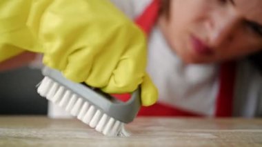 Kadın elleri sarı lastik eldivenlerle leke silmeye çalışıyor..